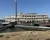 The image shows a large multi-deck paddlewheel riverboat docked at a pier, with a gangway leading to its entrance and a clear sky in the background.