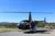 Two people are standing in front of a helicopter with