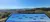 This image features a scenic overlook with a clear blue sky, mountainous horizon, and an educational panel indicating the names of various mountains visible in the distance.