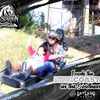 Two joyful riders are experiencing a mountain coaster ride, as shown in a promotional souvenir photo with text celebrating their ride on the longest mountain coaster in the Southeast.