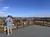A person is enjoying the view from an elevated observation deck overlooking a scenic town with rolling hills in the background.