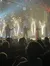 A band performs on stage with a dramatic display of indoor fireworks, as an enthusiastic audience watches the live concert.