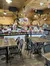 The image shows a cozy, festively decorated interior of a wooden building with Christmas decorations, multiple dining tables, and a counter area, suggesting it is a restaurant or café celebrating the holiday season.