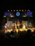 A group of bluegrass musicians is performing on stage in front of an attentive audience.