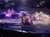 The image shows a theatrical performance with actors dressed in biblical-era costumes and live camels, likely depicting a scene related to a story from religious texts, in front of an audience seated in an arena-style theater.