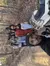 A group of people are posing for a selfie in the woods, with a person in the foreground holding the camera and an ATV nearby, signaling they might be enjoying an outdoor adventure.