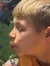 A boy in an orange shirt is looking through an aquarium glass at colorful fish swimming inside.