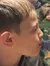 A boy is puckering his lips playfully at a group of colorful fish swimming in an aquarium.