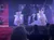 Performers in sparkly costumes are dancing on a stage decorated with lights and holiday decorations.
