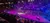 The image depicts a vibrant indoor equestrian performance with riders and horses under colorful stage lights, surrounded by an audience.