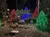 The image shows a festive Christmas display with trees lit in red, green, and blue lights, and a sign that reads