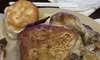 The image shows a plate with a roasted chicken and a biscuit.