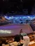 This image shows an indoor arena with a stage set depicting a snowy village scene, surrounded by audience seating, where guests are enjoying a live performance at Dolly Parton's Stampede.