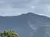 The image shows a mountain range under a cloudy sky with a few green trees in the foreground.