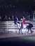 A person in a red outfit is riding a black and white horse in front of an audience.