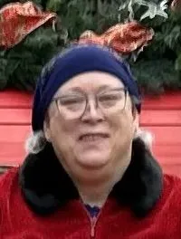 A person is sitting in a festively decorated red sleigh with two white polar bear statues in front.