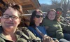 A group of four people are sitting together outside on a sunny day, smiling for a photo.