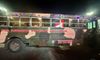 A camouflaged tour bus, decorated with colorful lights, advertises