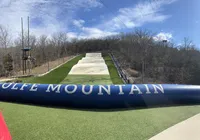 The image shows a dry ski slope on a hill with the name