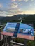 The image shows a scenic skybridge, with an informational sign detailing its engineering marvels, set against a backdrop of green hills and a partly cloudy sky.