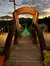 The image shows the entrance to the illuminated SkyBridge in Gatlinburg, framed by a wooden arch, with a scenic mountain backdrop at sunset.