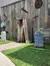 The image depicts an old wooden fence adorned with rusty tools and humorous tombstones, creating a rustic western setting.
