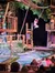 A performer is swinging on a rope over a water pool in front of an audience at a theatrical stage setup.