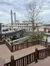 A large riverboat with two tall smokestacks is docked beside a wooden walkway and stairway under a cloudy sky.