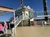 People are standing on the deck of a steamboat with intricate railings and a clear blue sky in the background.