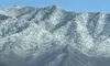 Snow-covered mountains rise against a clear blue sky.