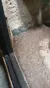 Two small turtles are resting against a rock wall in a glass enclosure.
