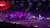 A group of riders on horseback, dressed in patriotic attire, parades in an arena carrying American flags under colorful stage lighting.