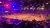 The image depicts an indoor arena with a Western-themed performance, where horse riders carrying American flags entertain a seated audience under colorful stage lights.