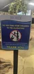 A humorous sign at an aquarium warns visitors not to feed their children to the alligators and asks them to stay behind the barricade for safety.