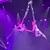 Two aerial performers gracefully execute a ballet-inspired pose suspended in mid-air with vibrant stage lighting.