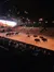 The image shows a large indoor arena with people watching a live show featuring horseback riders and roaming bison.