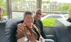 Two people are sitting closely together and smiling inside a bus near an emergency exit.