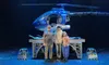 Three people are standing on a stage in front of a futuristic blue helicopter model.