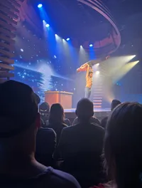 A performer on stage is holding another person overhead as part of an acrobatic act, in front of an audience.