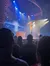 A performer on stage is holding another person overhead as part of an acrobatic act, in front of an audience.