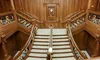 An ornate wooden staircase with intricate railings and detailed carvings is displayed in a luxurious interior setting.