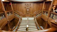 An ornate wooden staircase with intricate railings and detailed carvings is displayed in a luxurious interior setting.