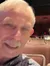 An older couple is taking a selfie in a theater with empty rows of seats behind them.