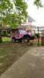 A pink jeep used for tours is parked on a rock in front of a quaint building labeled