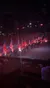 Riders on horses, holding American flags and adorned with red lights, perform in an arena with an audience.