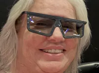 Three people are sitting in a theater wearing 3D glasses and smiling at the camera.