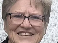 A couple is standing in front of a cascading waterfall feature in a scenic outdoor setting.