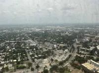 Aerial view of a sprawling urban landscape seen through a rain-speckled window.
