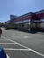 A person walks near a classic, shiny diner with a red awning under a clear blue sky.