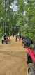 A group of people wearing helmets are gathered around off-road vehicles in a forested area.